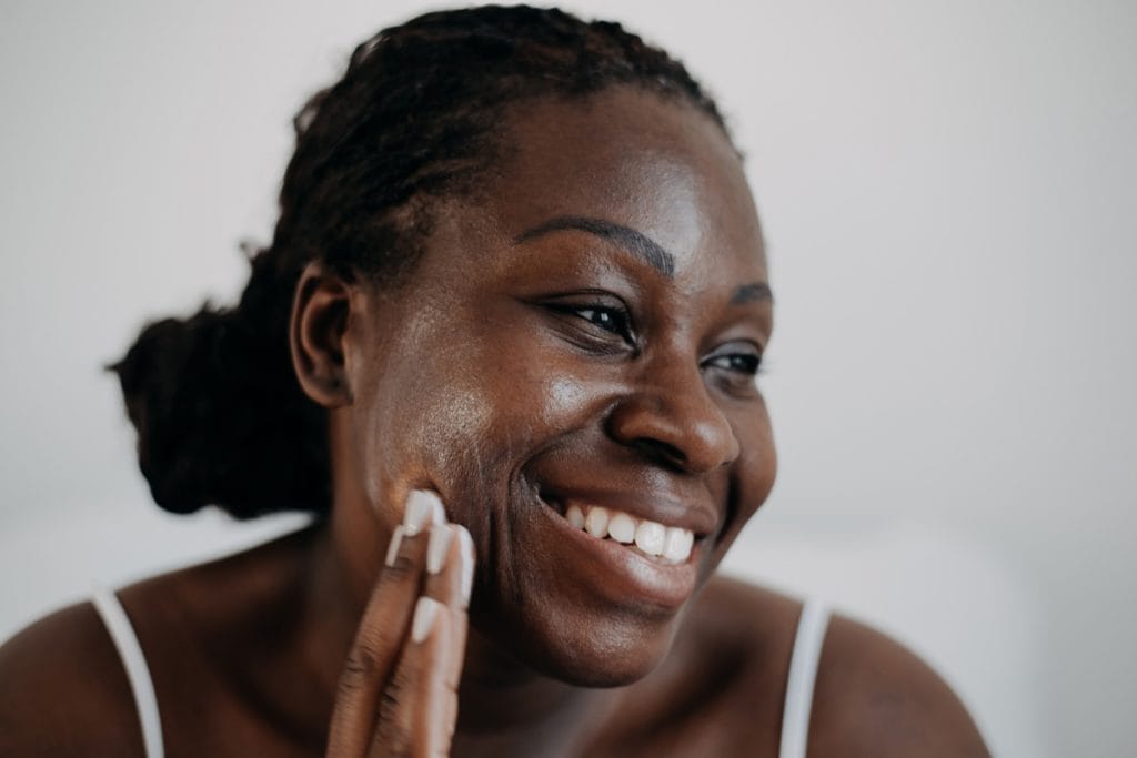 African American woman smiling and touching her face