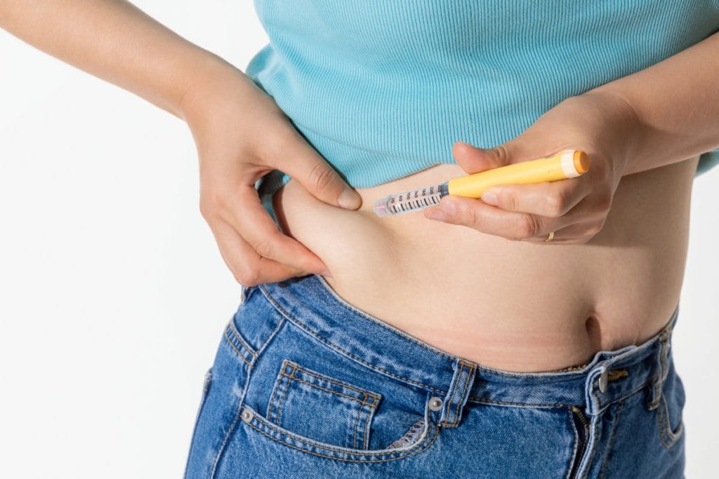 Woman injecting weight loss medication into her stomach